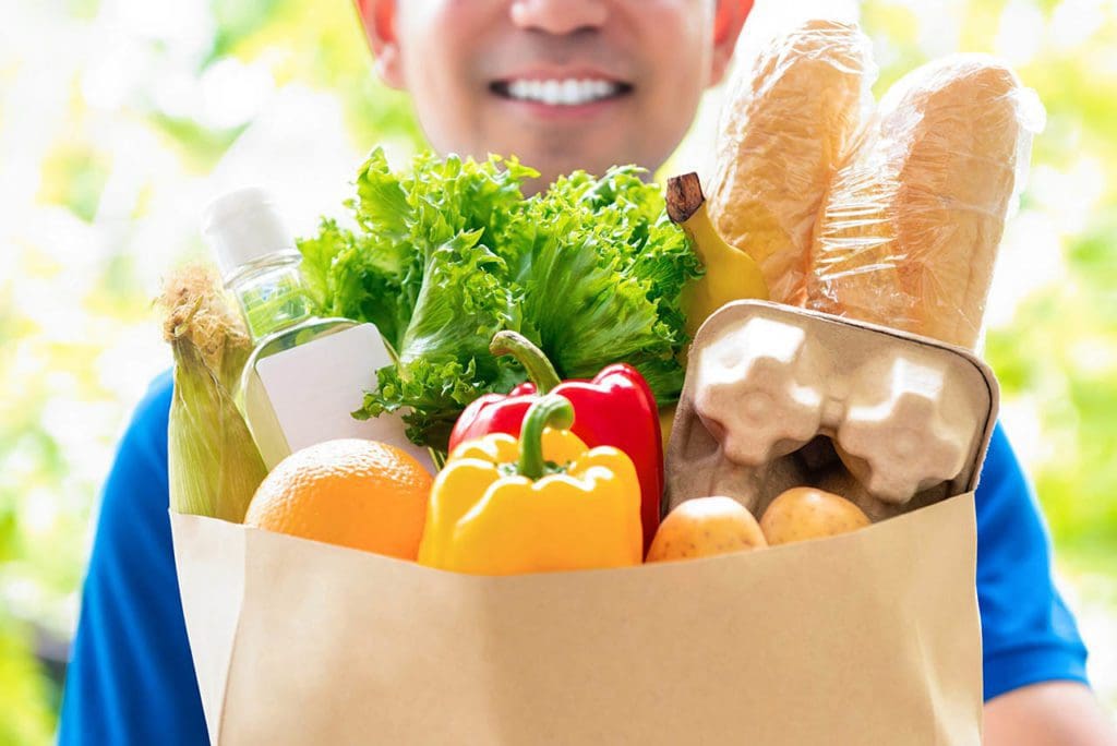 Image of person holding a bag of groceries to deliver